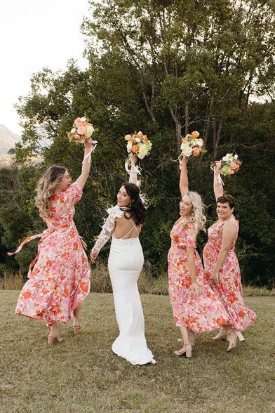 A bride and her bridesmaids are holding their bouquets in the air.