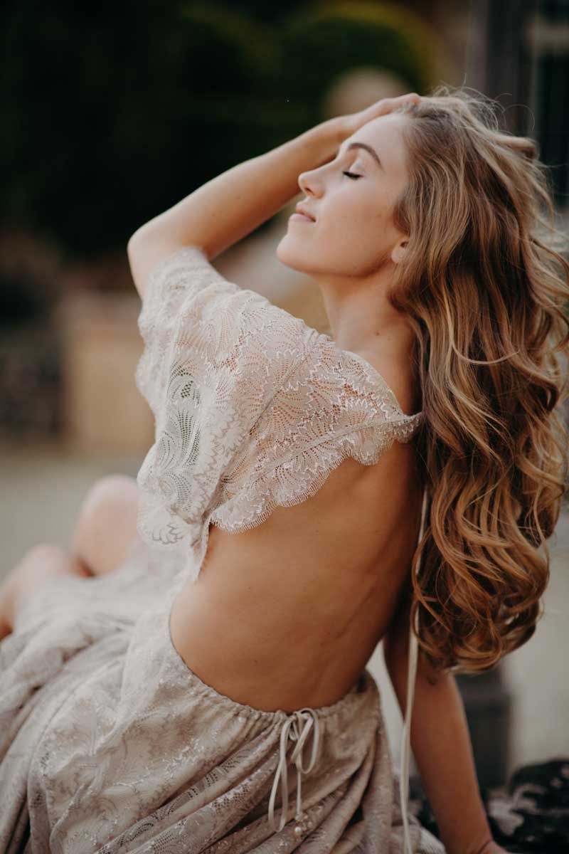 A woman in a lace dress is sitting down with her eyes closed.