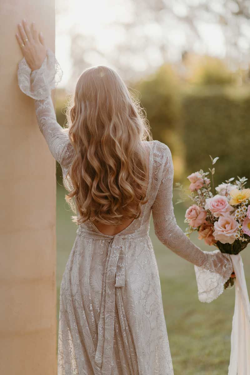 The bride is wearing a white lace dress and holding a bouquet of flowers.