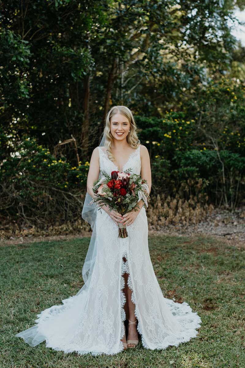 The bride is wearing a white wedding dress and holding a bouquet of flowers.