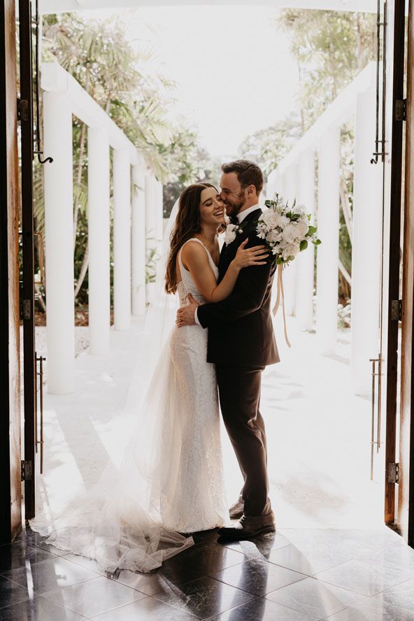 A bride and groom are kissing in front of a door.