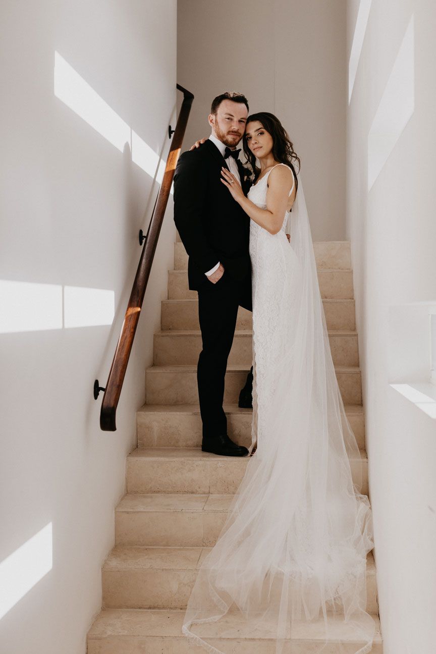 A bride and groom are posing for a picture on a set of stairs.