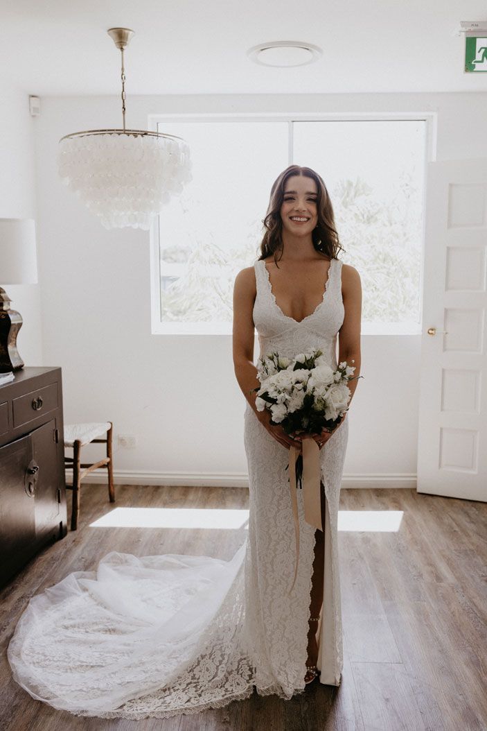 A bride in a wedding dress is holding a bouquet of flowers in a room.