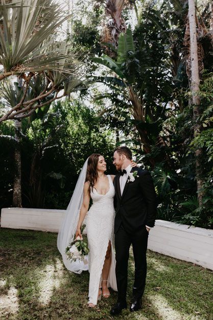 A bride and groom are standing next to each other in a garden.