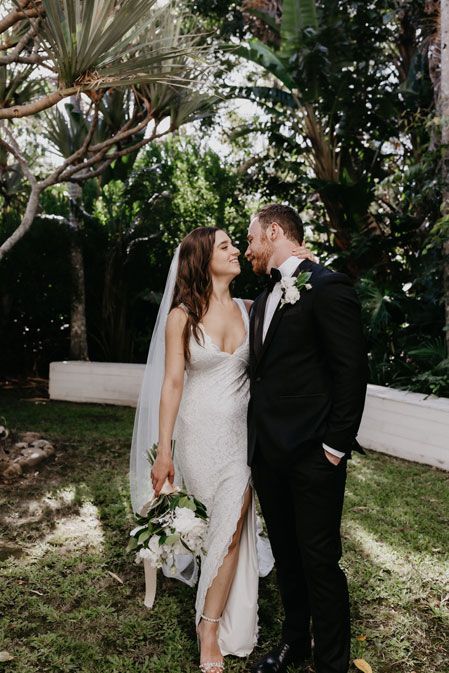 A bride and groom are kissing in a garden on their wedding day.