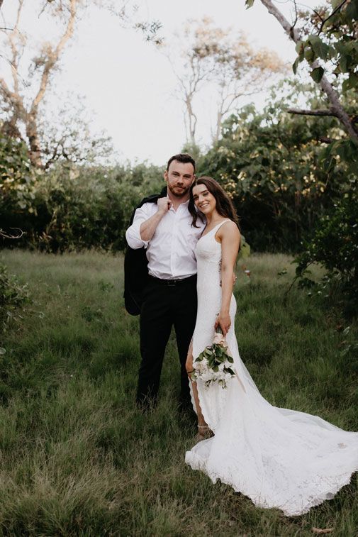 A bride and groom are posing for a picture in a field.