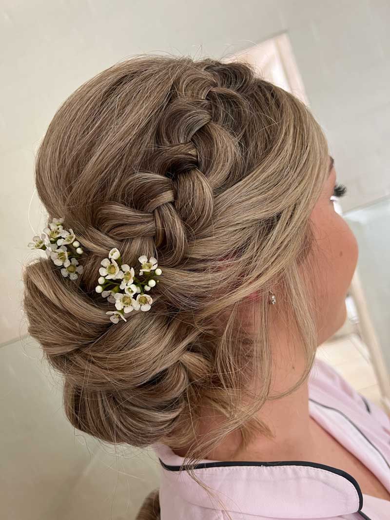A woman is wearing her hair in a bun with flowers in it.