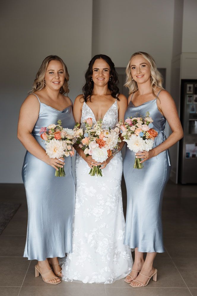 A bride and her bridesmaids are posing for a picture while holding bouquets of flowers.