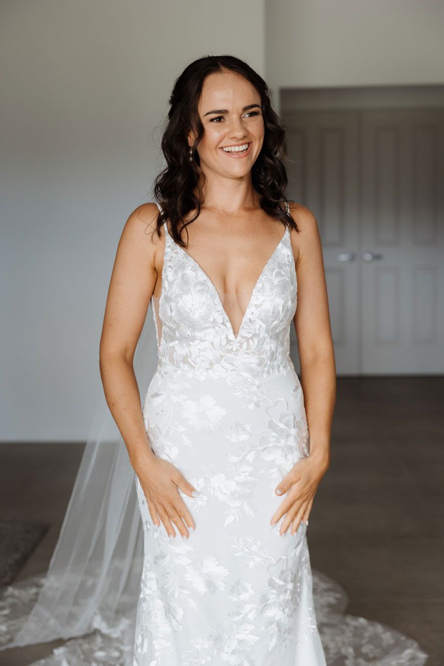 A woman in a white wedding dress is standing in a room.
