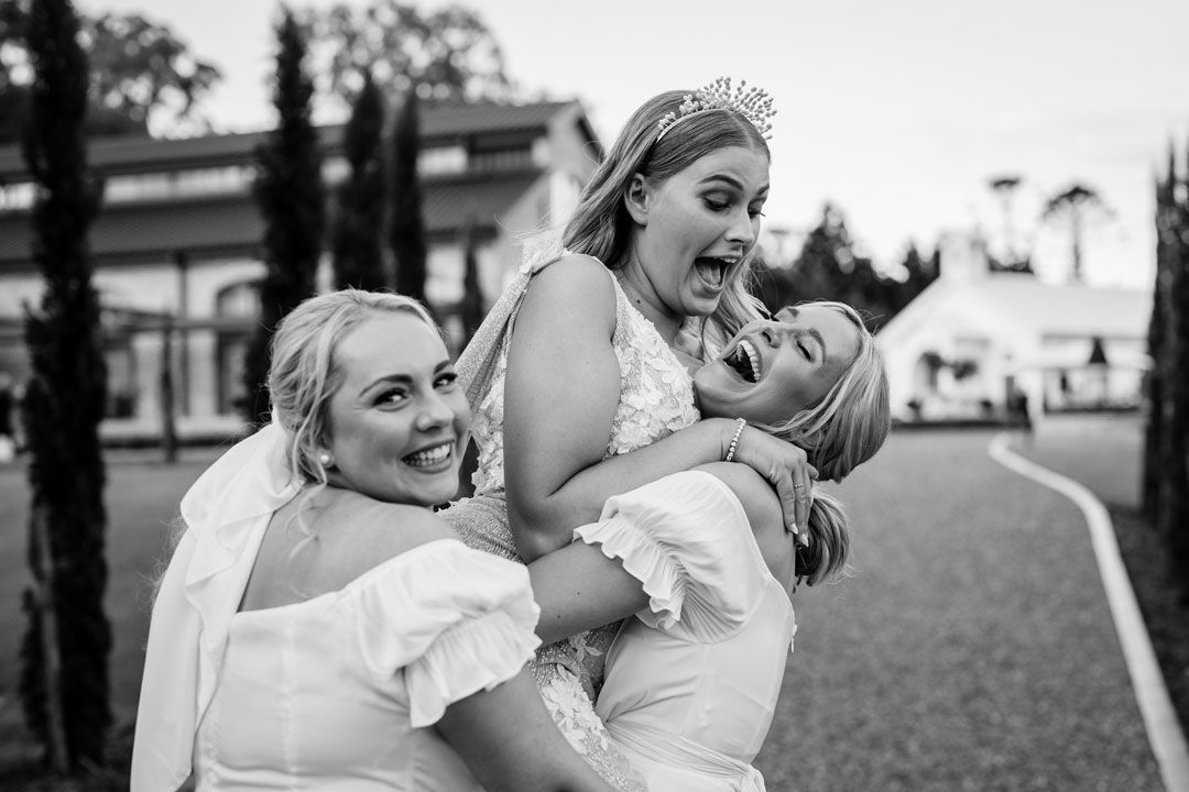 A bride and her two bridesmaids are posing for a black and white photo.