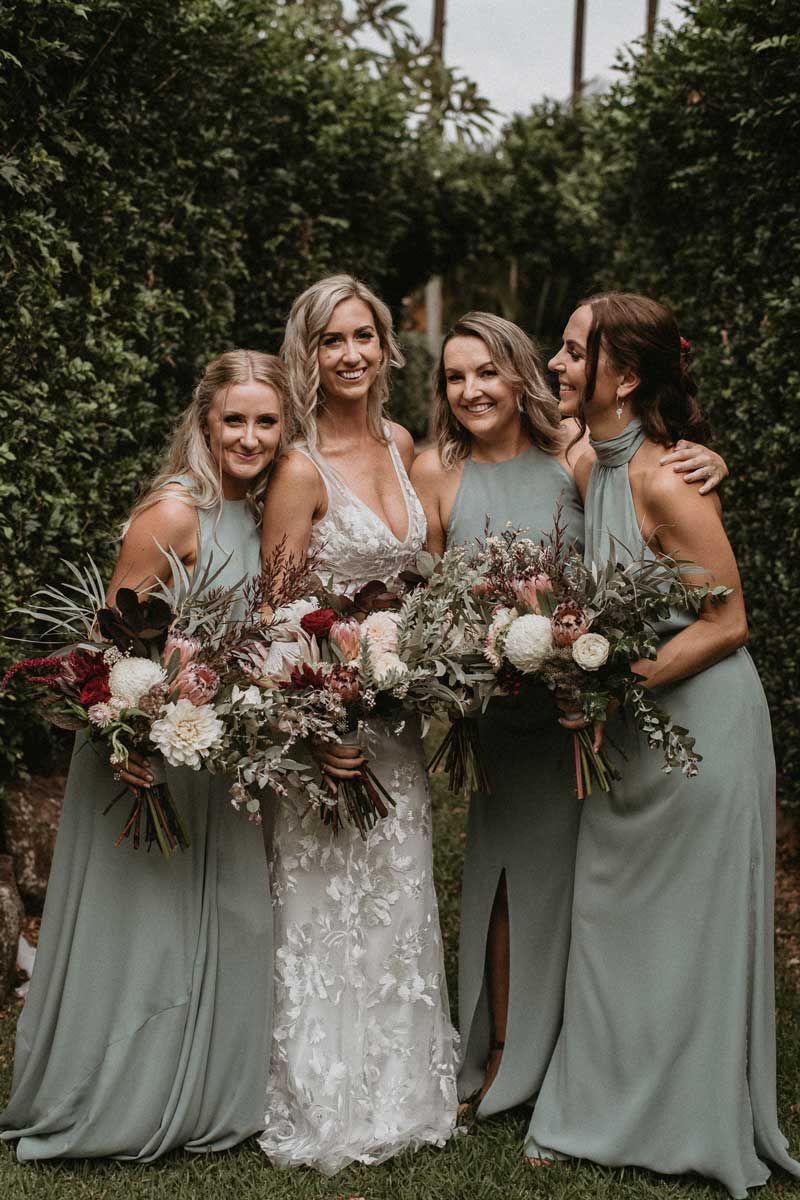 A bride and her bridesmaids are posing for a picture while holding bouquets of flowers.