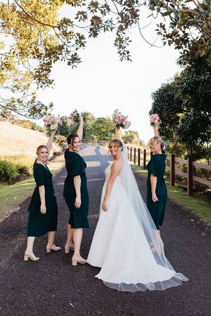 A bride and her bridesmaids are posing for a picture on a road.