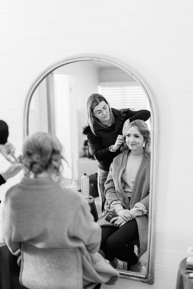 A woman is getting her hair done in front of a mirror.