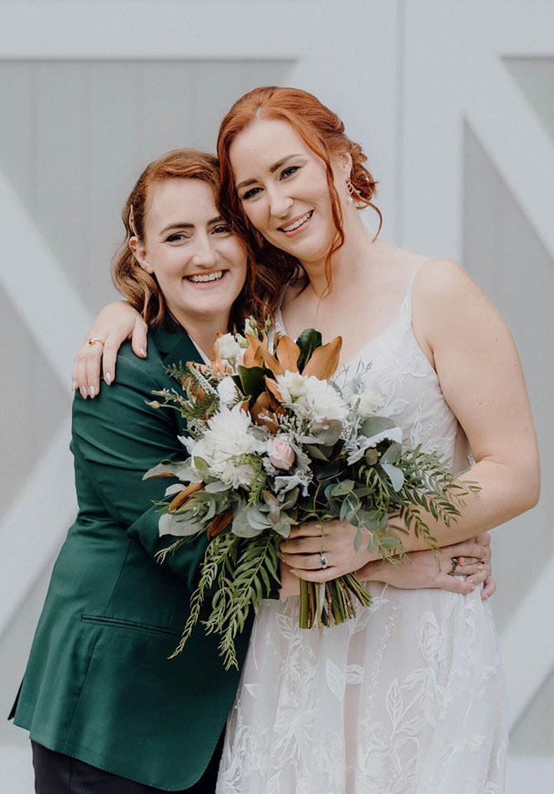 Two women are standing next to each other holding a bouquet of flowers.