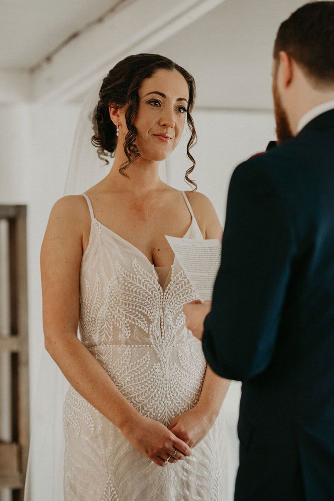 A bride and groom are holding hands during their wedding ceremony.