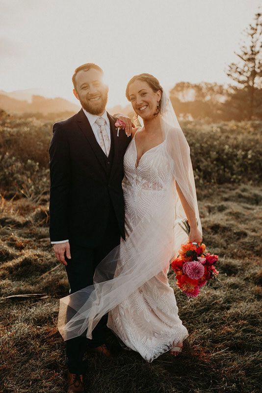 A bride and groom are posing for a picture in a field at their wedding.