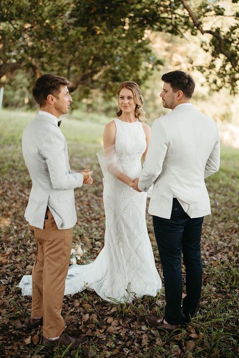 A bride and groom are holding hands during their wedding ceremony.