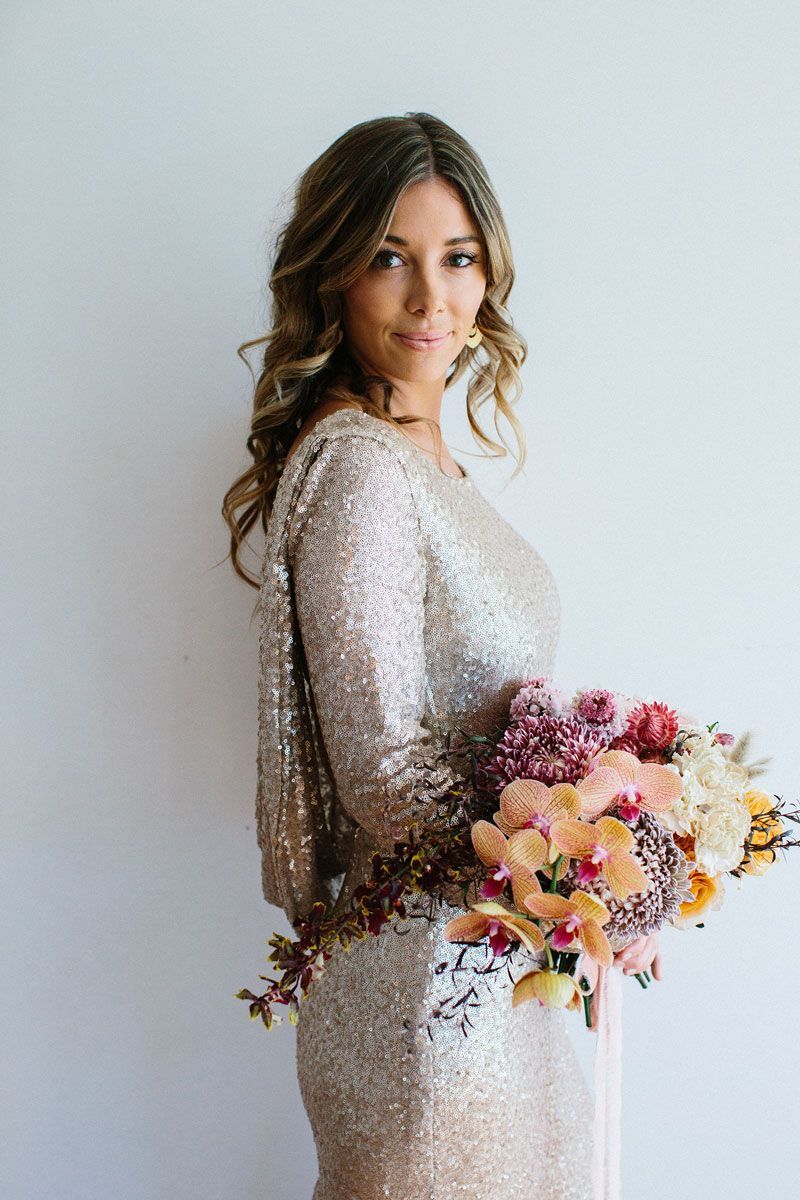 A woman in a sequined dress is holding a bouquet of flowers.