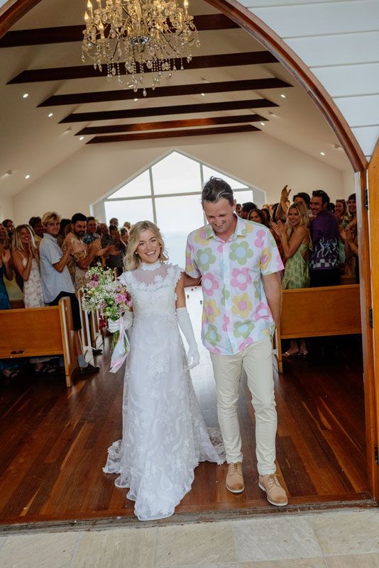 A bride and groom are walking down the aisle of a church.