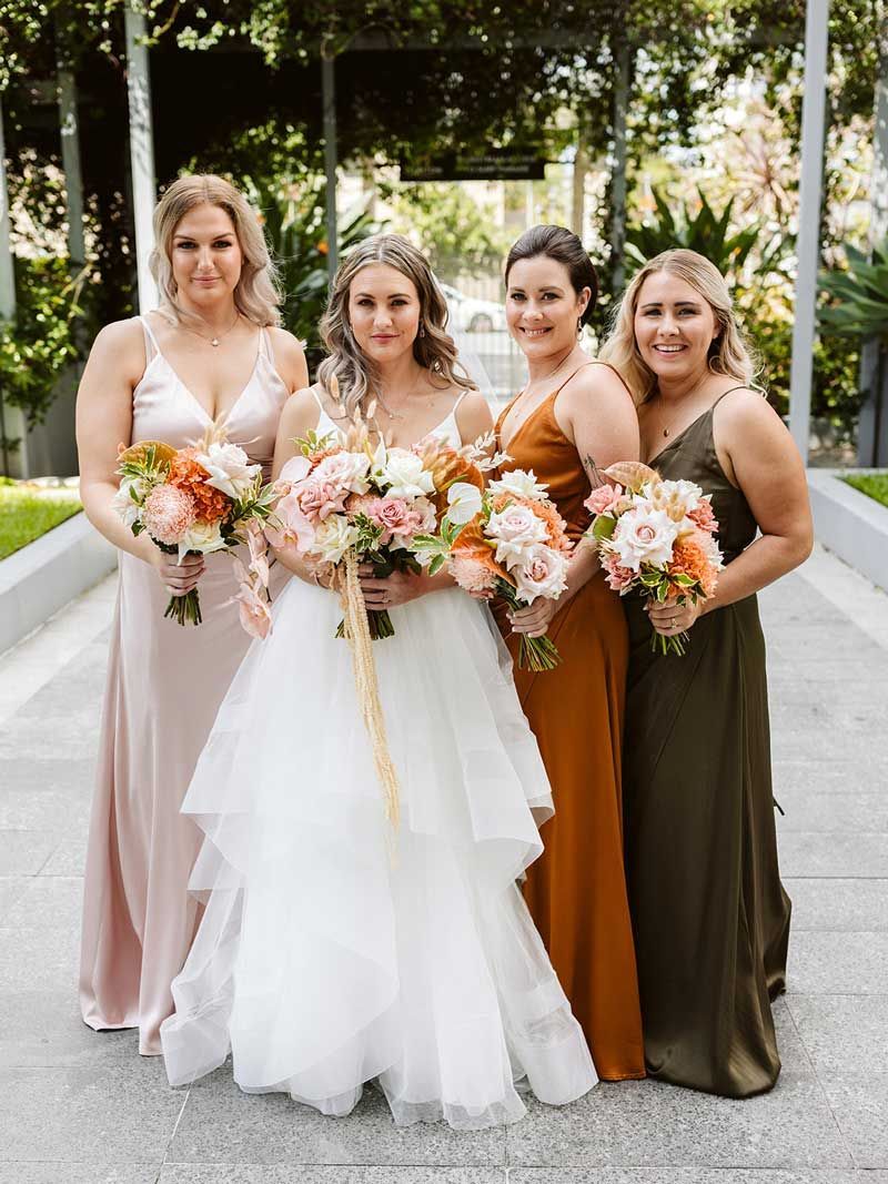 A bride and her bridesmaids are posing for a picture.
