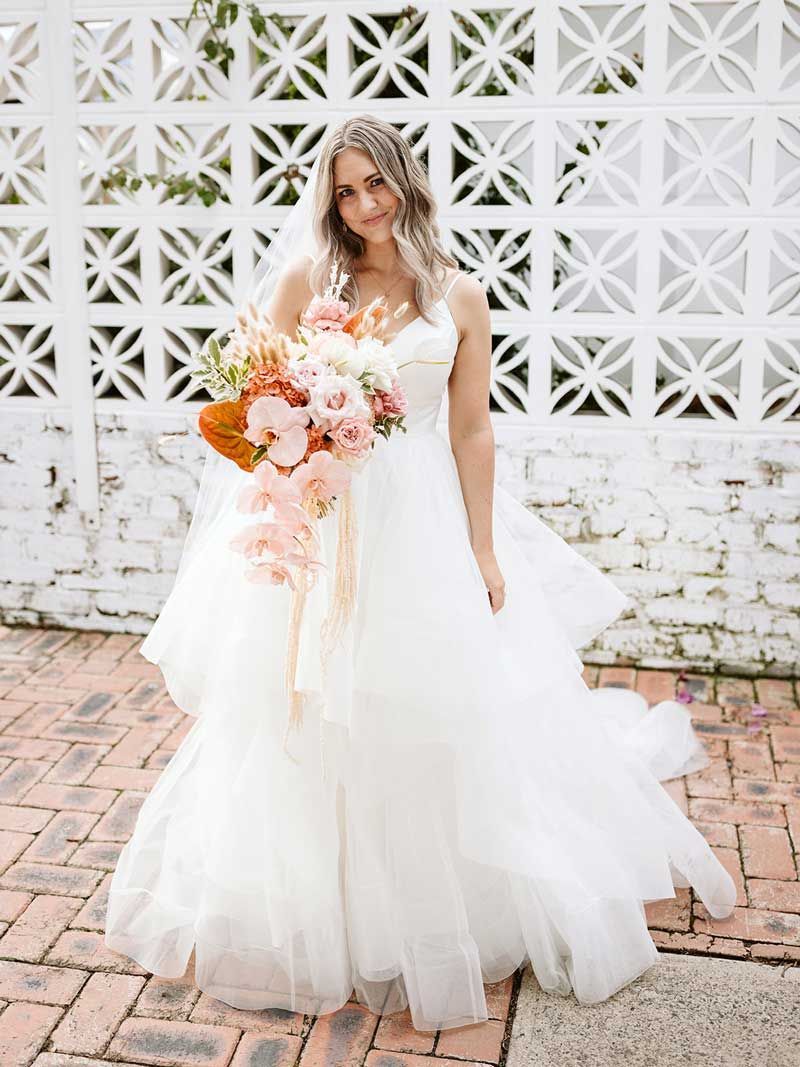The bride is wearing a white wedding dress and holding a bouquet of flowers.