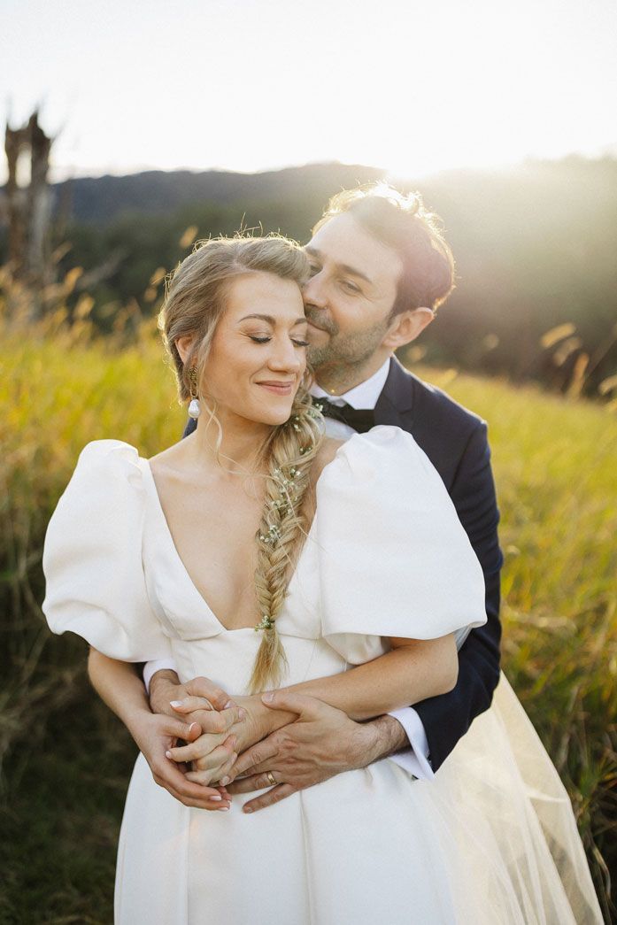 A bride and groom are posing for a picture in a field.