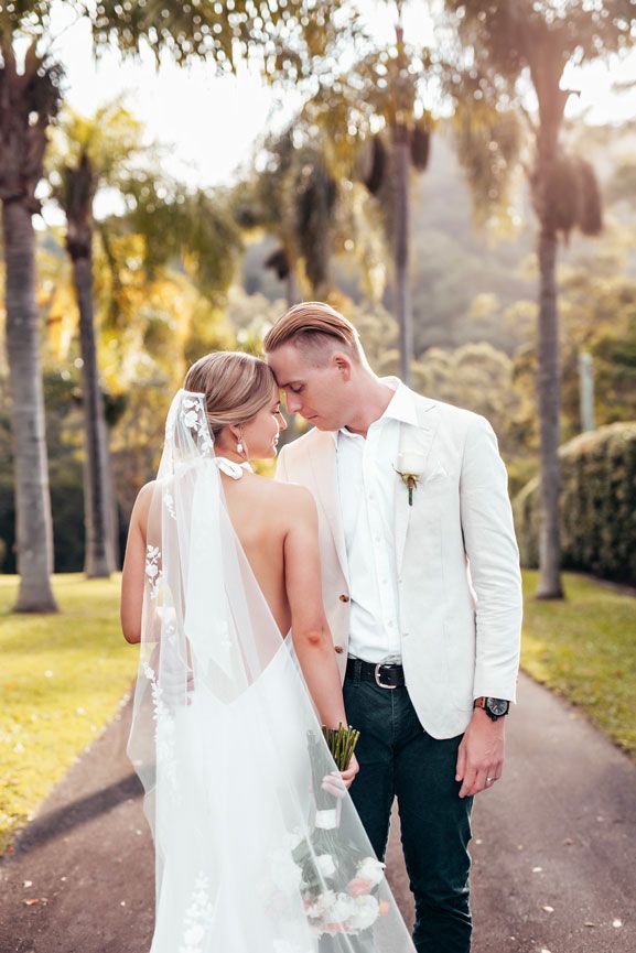 A bride and groom are standing next to each other on a path.