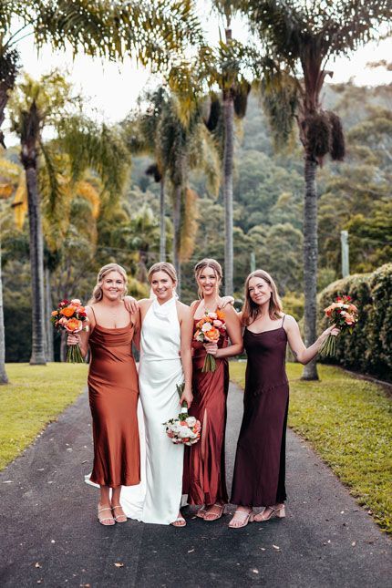 A bride and her bridesmaids are posing for a picture in front of palm trees.