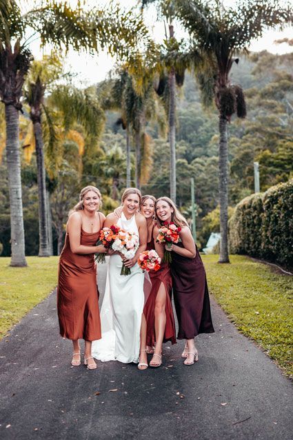 A bride and her bridesmaids are posing for a picture on a road.