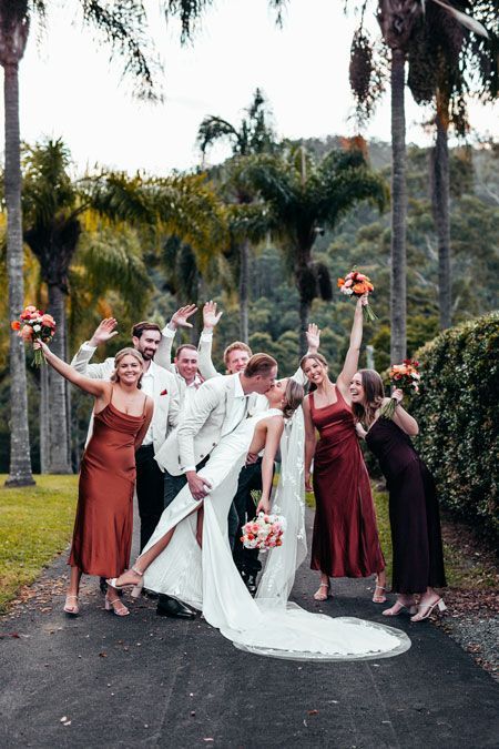 A bride and groom are posing for a picture with their wedding party.