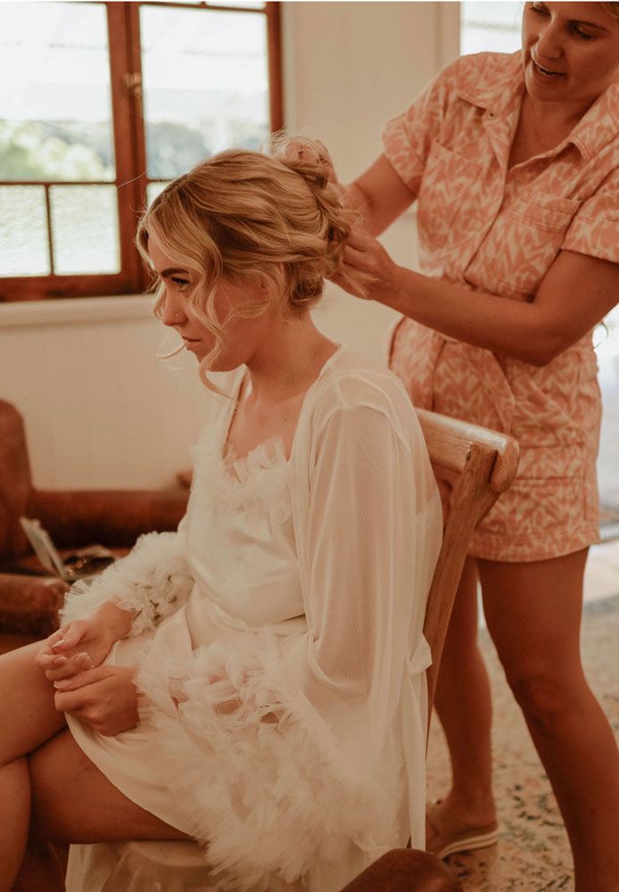 A woman is getting her hair done by a hairdresser while sitting in a chair.