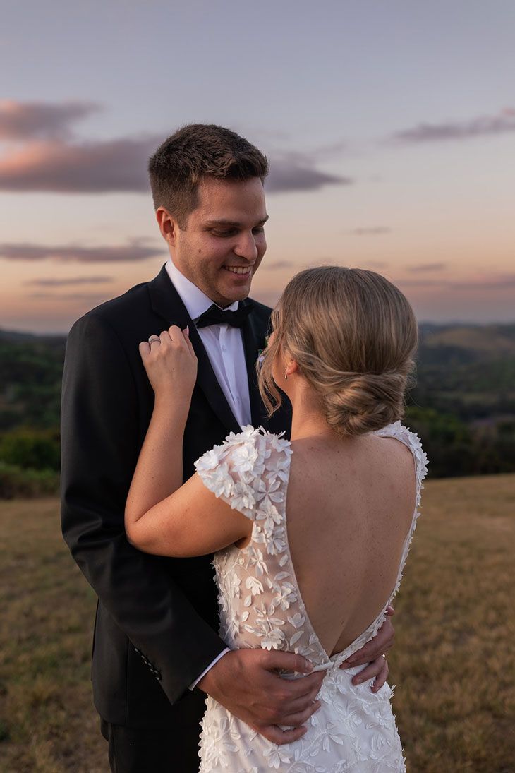 A bride and groom are posing for a picture in a field at their wedding.