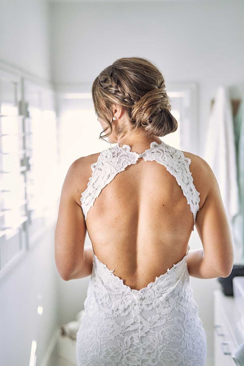 The back of a woman in a wedding dress is shown.