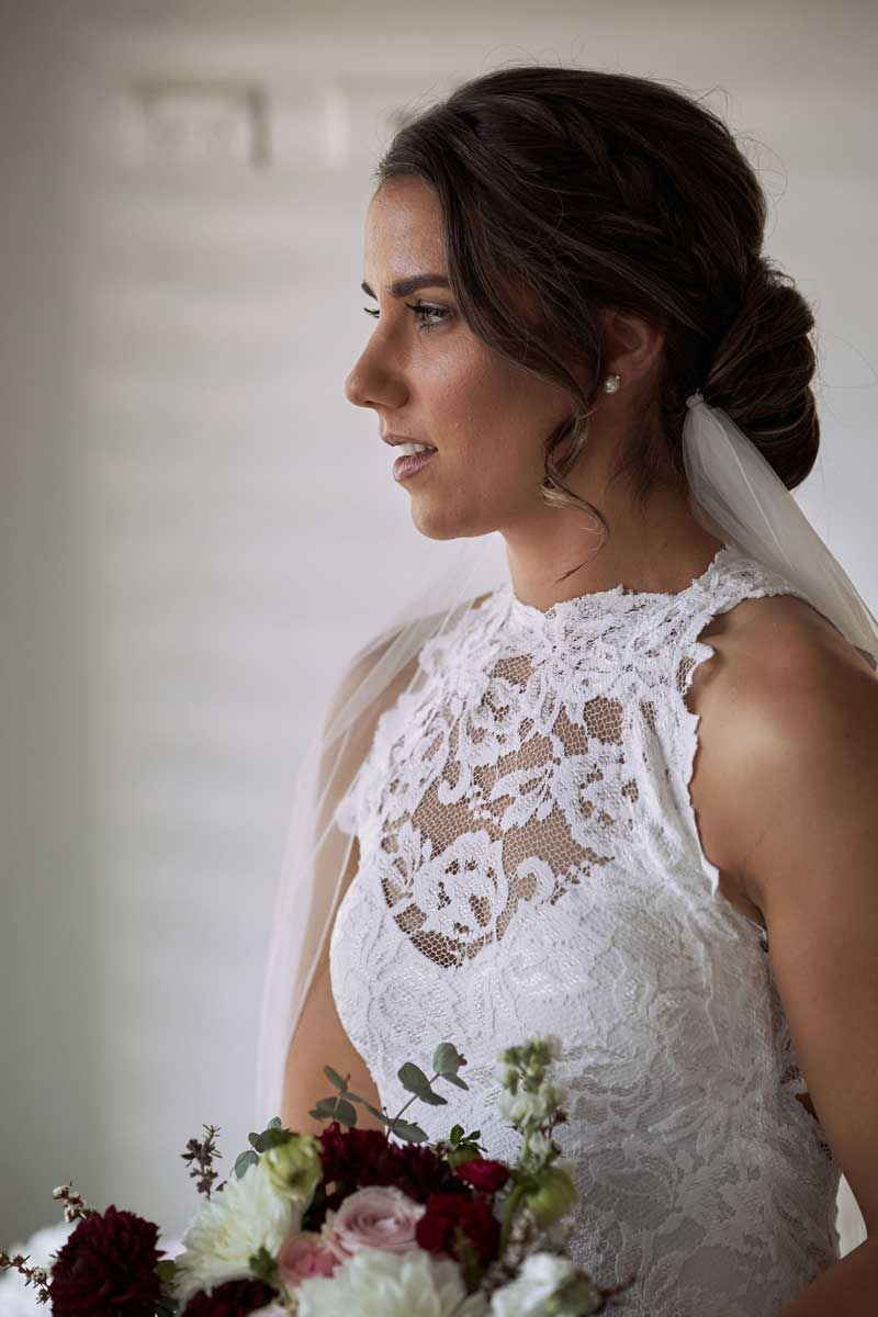 The bride is wearing a white lace dress and holding a bouquet of flowers.