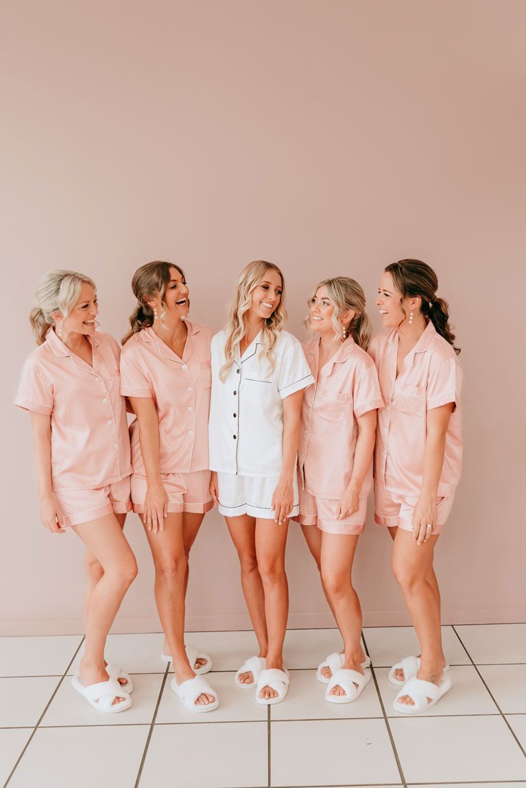 A bride and her bridesmaids are standing next to each other on a tiled floor.