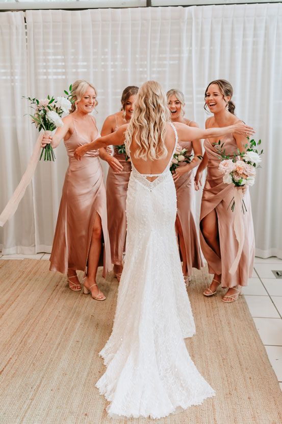 A bride and her bridesmaids are standing next to each other in a room.