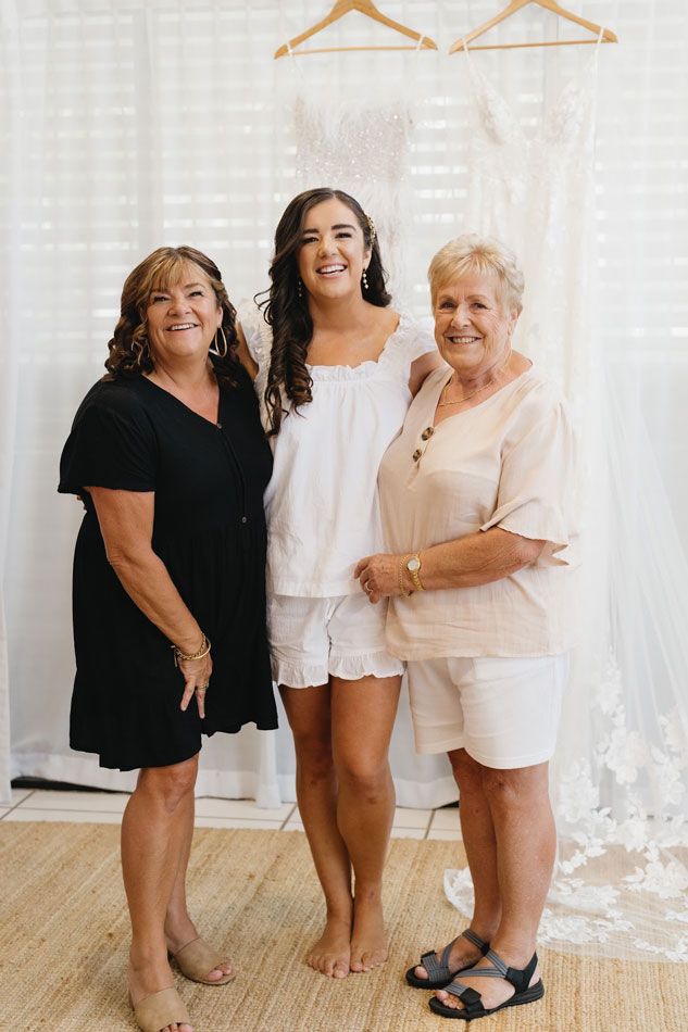 Three women are posing for a picture in front of a wedding dress.