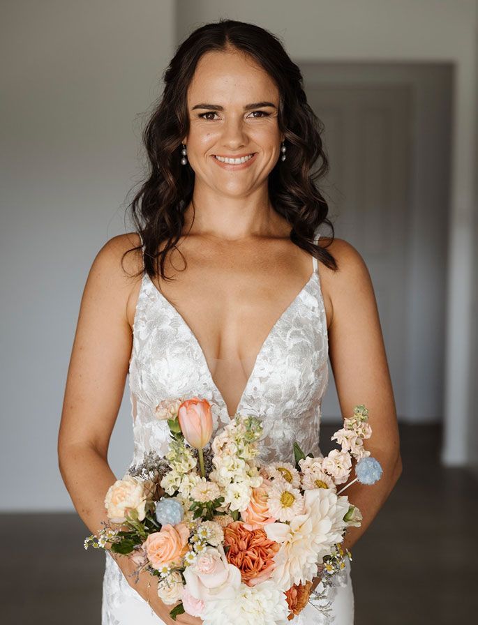 A woman in a wedding dress is holding a bouquet of flowers.