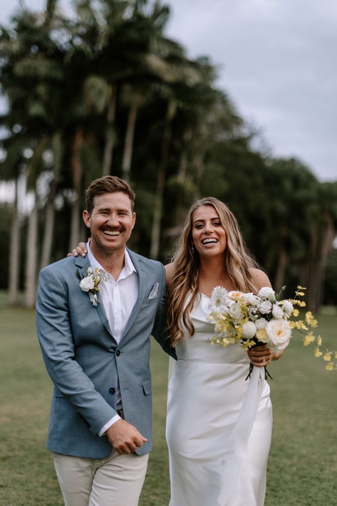 A bride and groom are posing for a picture in a field.