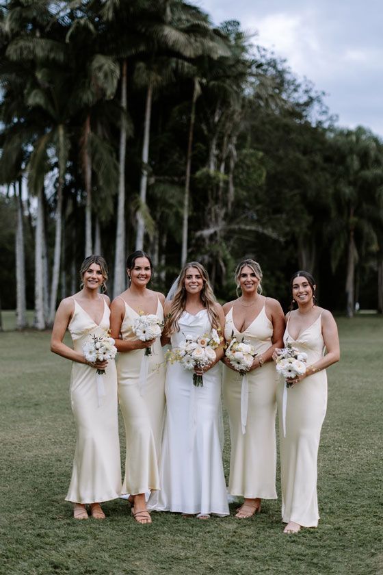 A bride and her bridesmaids are posing for a picture in a field.