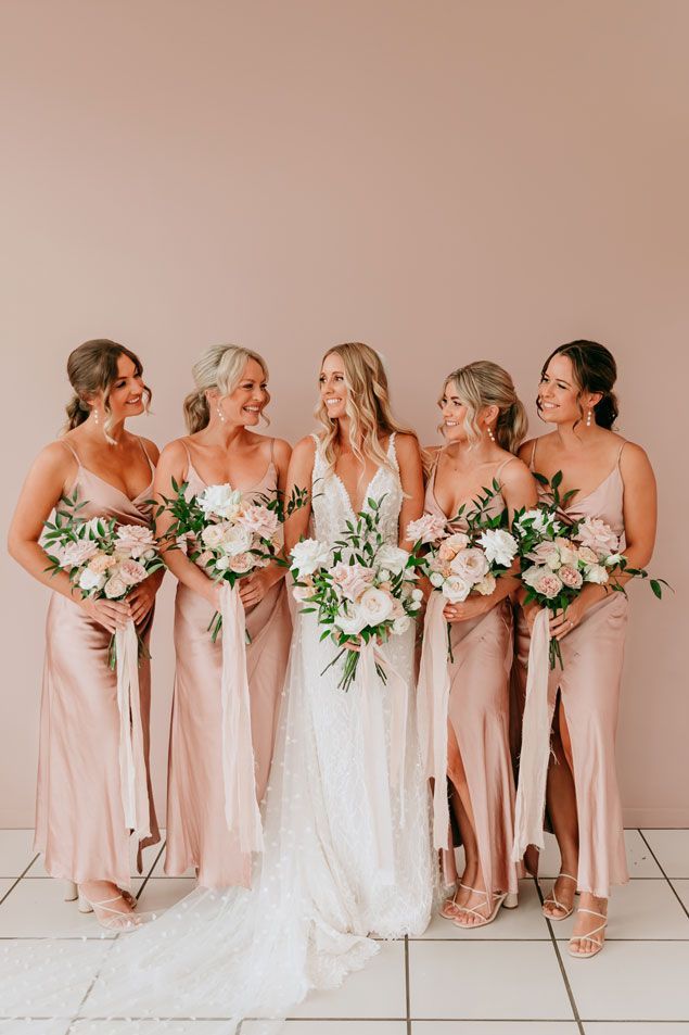 A bride and her bridesmaids are posing for a picture together.
