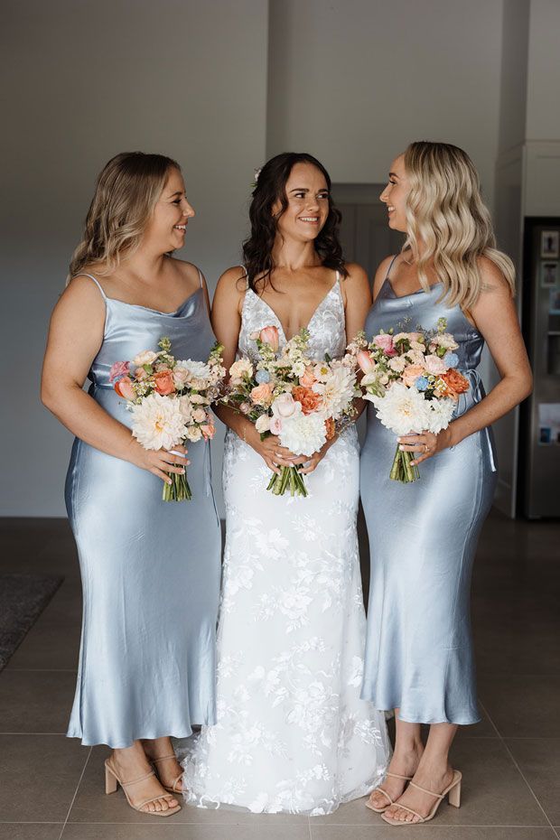A bride and her bridesmaids are standing next to each other holding bouquets of flowers.