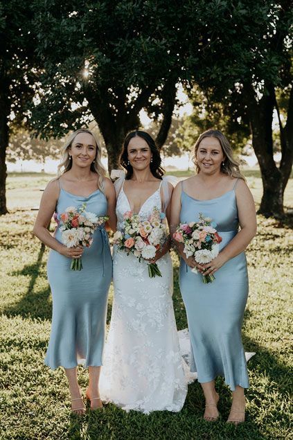 A bride and her bridesmaids are posing for a picture in the grass.