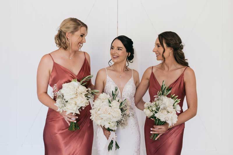 A bride and her bridesmaids are standing next to each other holding bouquets of flowers.