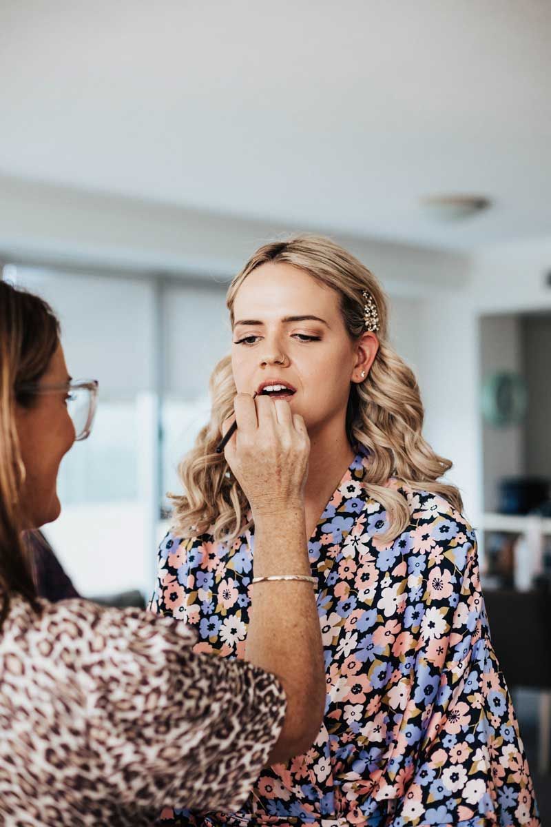 A woman is getting her makeup done by a makeup artist.
