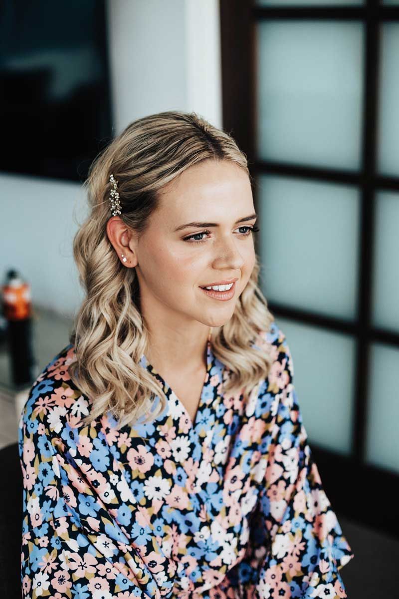 A woman in a floral robe is getting ready for a wedding.