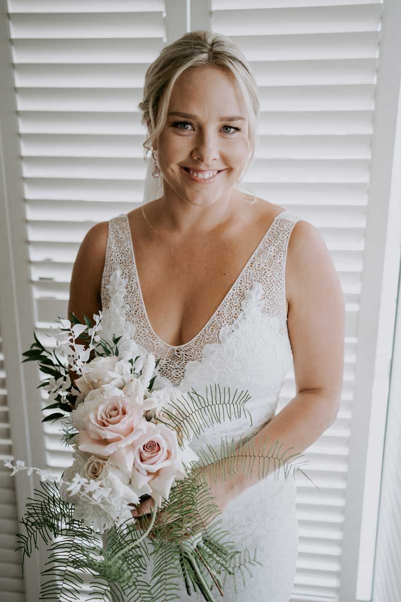 The bride is wearing a white dress and holding a bouquet of flowers.