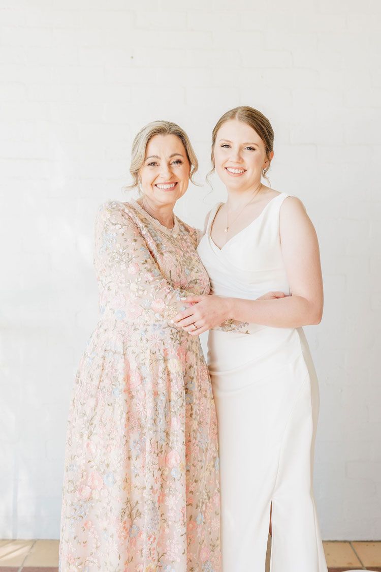Two women in white dresses are posing for a picture together.
