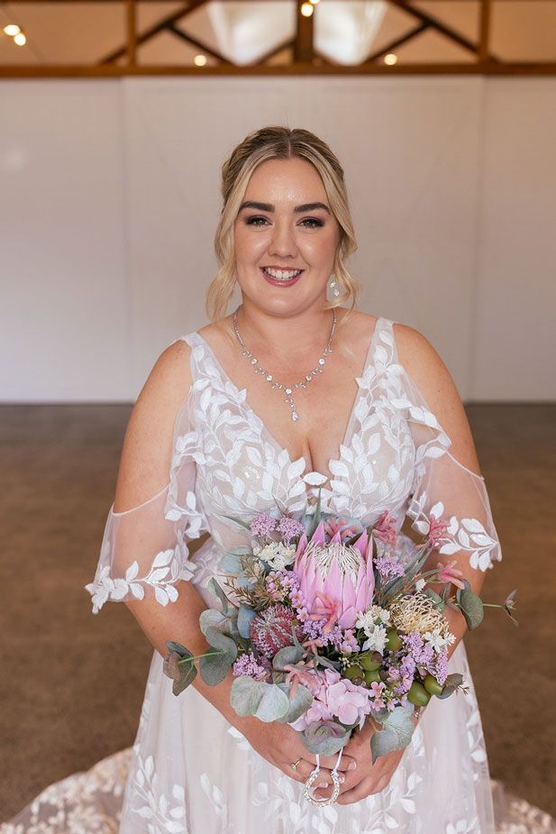 A woman in a wedding dress is holding a bouquet of flowers.