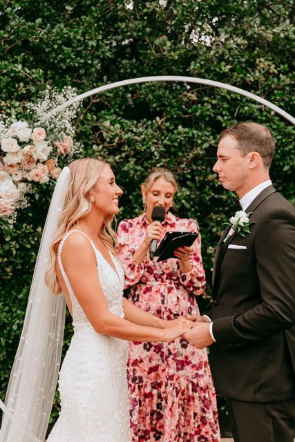 A bride and groom are holding hands during their wedding ceremony.